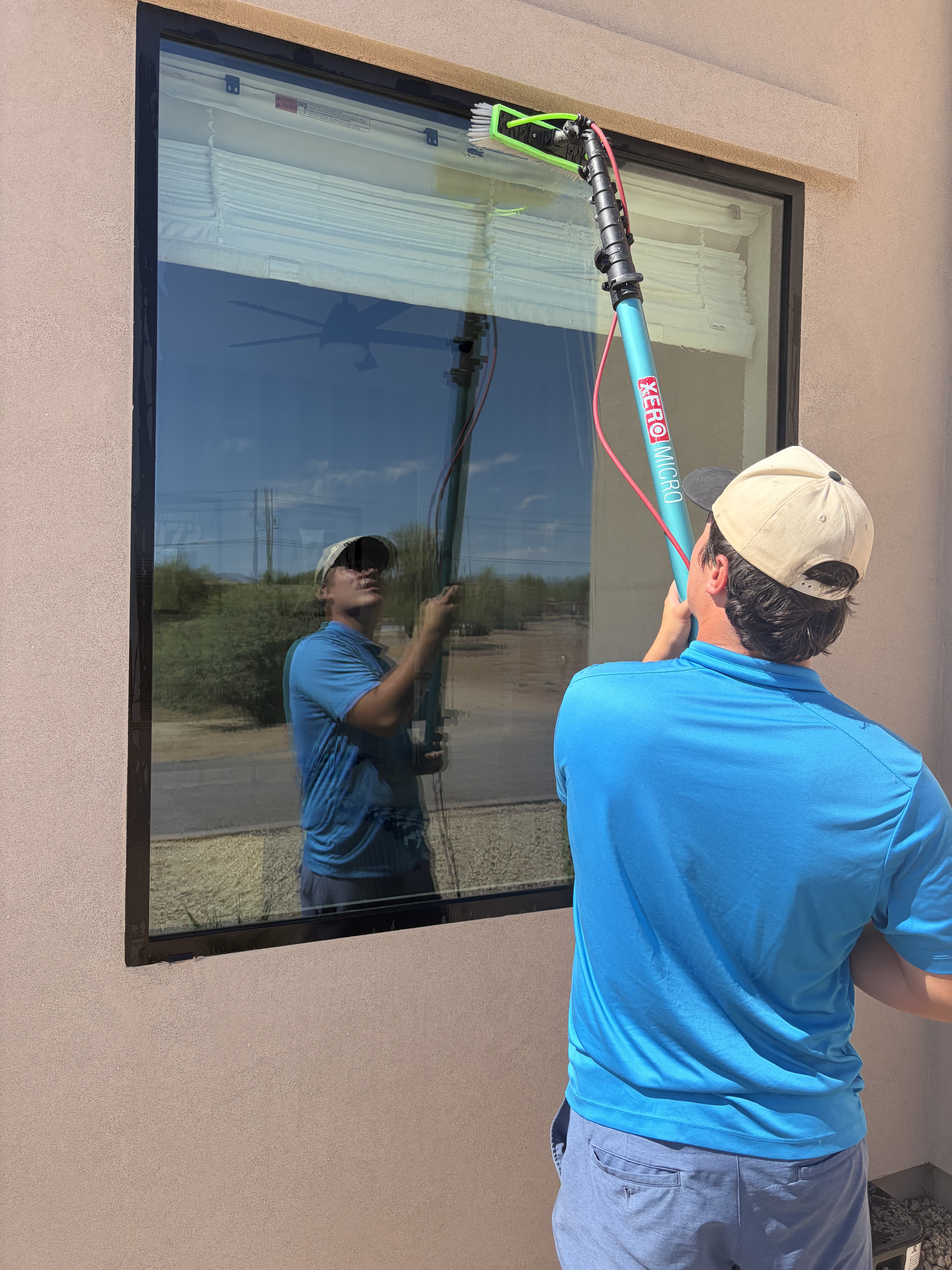 Technician using waterfed pole to detail glass